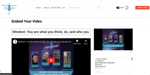 Screenshot of the 'Reduce The Stigma' website featuring a section to embed a video. The video title is 'Mindset: You are what you think, do, and who you interact with.' Below the title is a video thumbnail showing four speakers: Whitney, Dr. Mo, Roger Carroll Jr., and Angel Piller, with the text 'Mindset Strategies for Overcoming Challenges & Thriving' and 'Live stream recorded 6/25/24.' The website header includes a logo, navigation options (Browse, About Us, Recovery Shop, Cart), a search bar, a toggle for NSFW content, and a 'Submit Video' button. There is also a category selection dropdown and a tag input field on the right side.